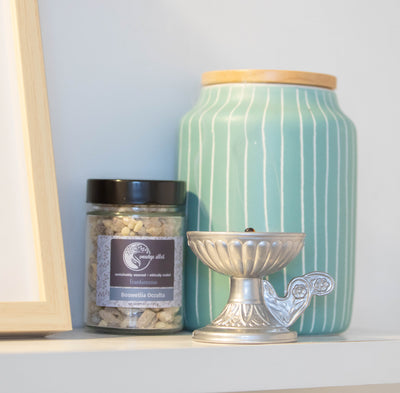 Jar of Boswellia Occulta resin next to brass burner and teal vase